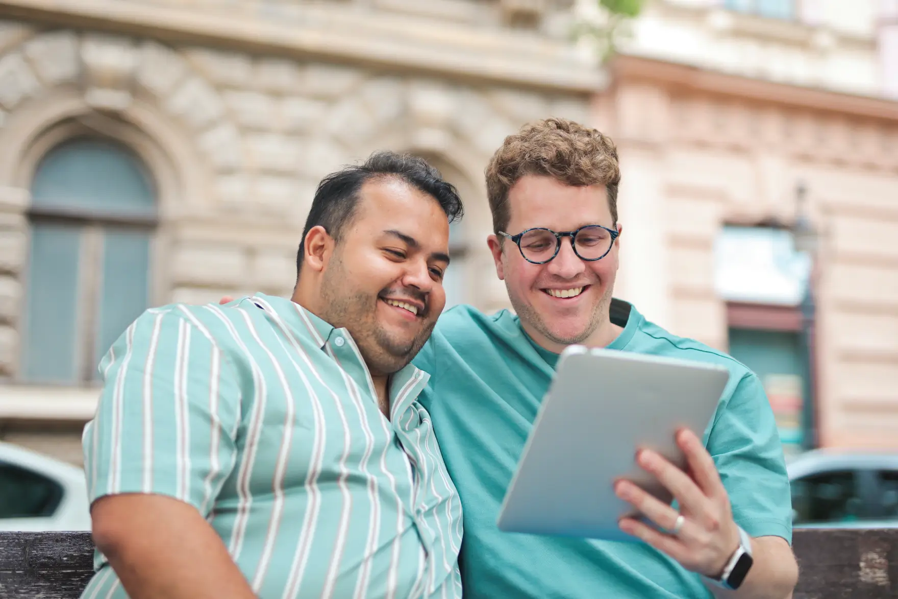 two-men-hug-each-other-bench-use-tablet