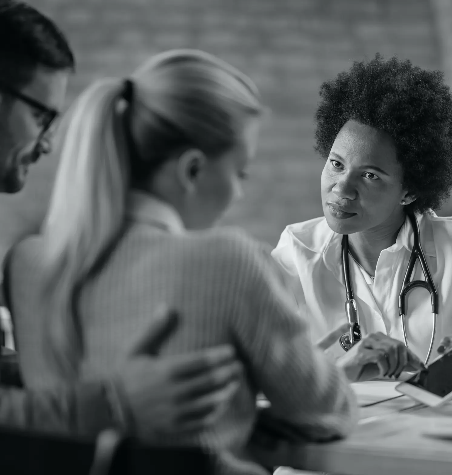 A female doctor showing couple their electronic medical record touchpad